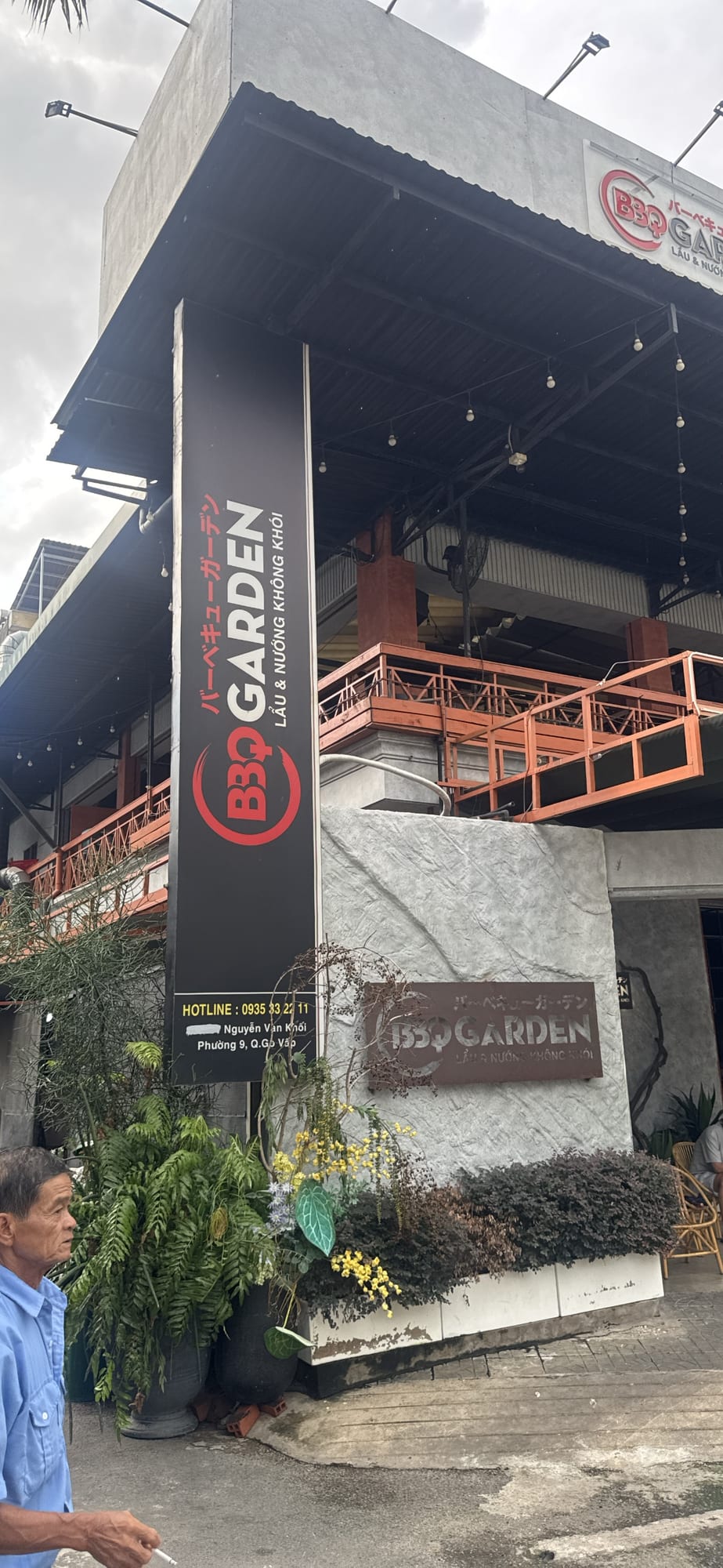 Exterior of BBQ Garden restaurant showing black and orange signage, rooftop terrace, and concrete facade