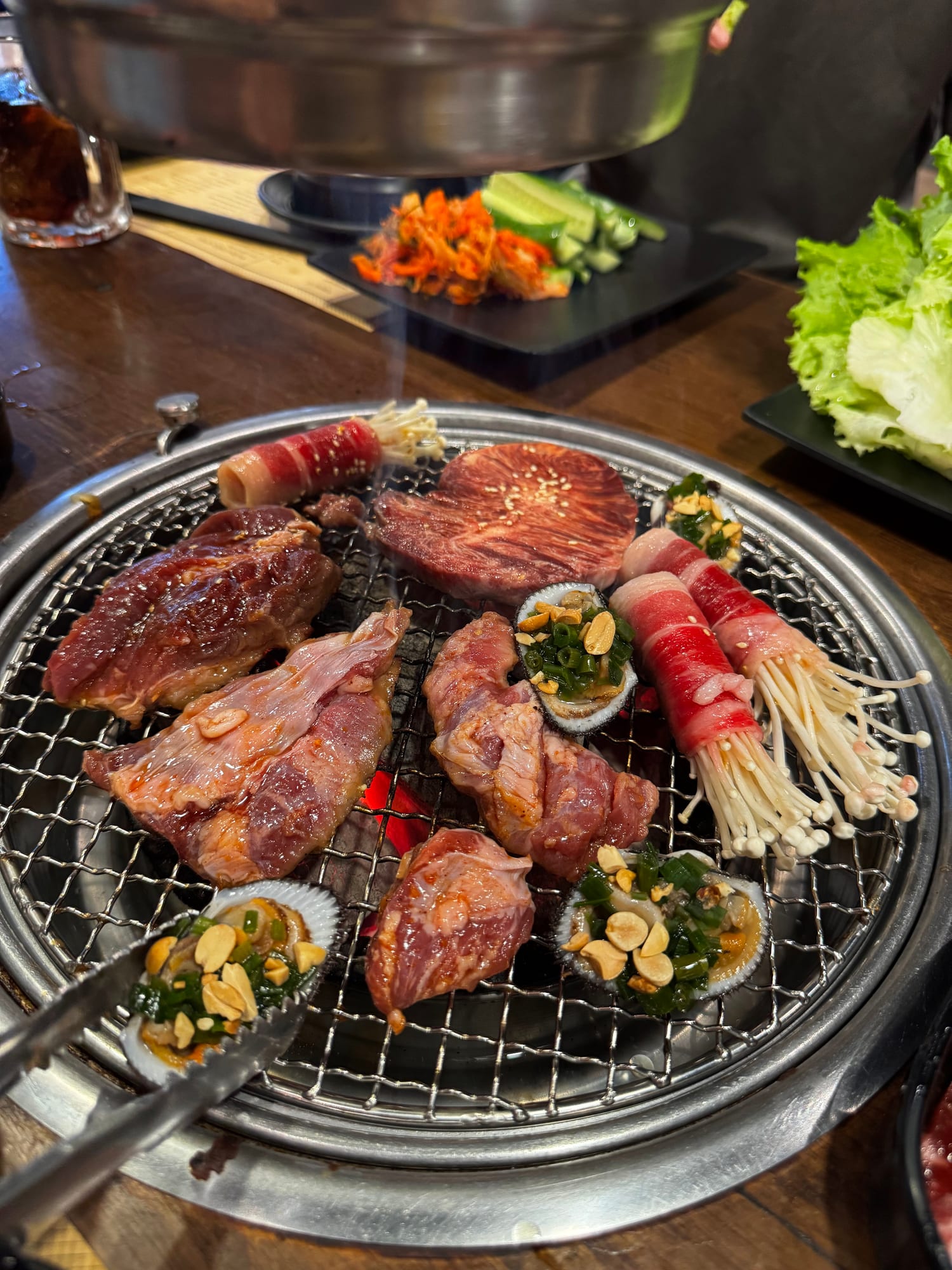 Grilled meat cuts, fresh vegetables, and side dishes on a Korean-style BBQ table